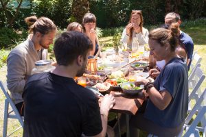 Family Gathered Around A Table Outside Eating Dinner