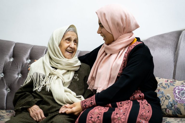 A Younger Woman And An Older Woman Sitting On A Couch Together.