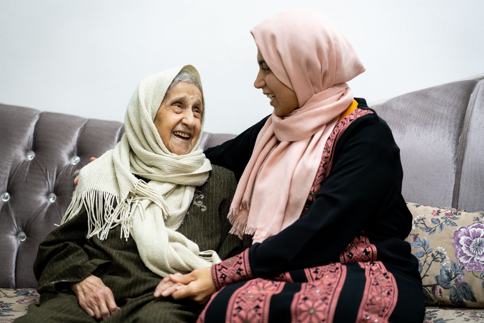 A younger woman and an older woman sitting on a couch together.